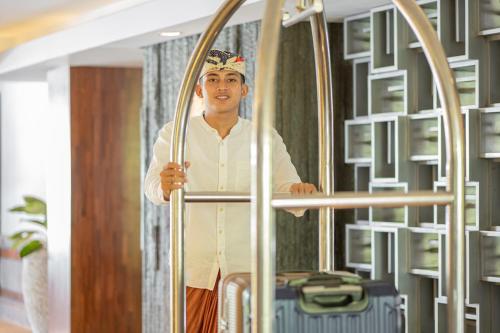 a man standing next to a bed with luggage at Prime Plaza Suites Sanur – Bali in Sanur