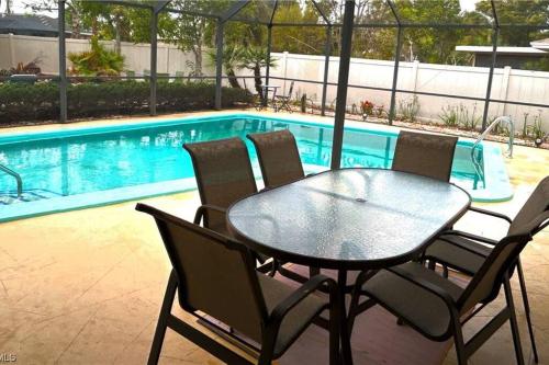 a table and chairs next to a swimming pool at Beautiful 3 Bed House with pool in North Fort Myers