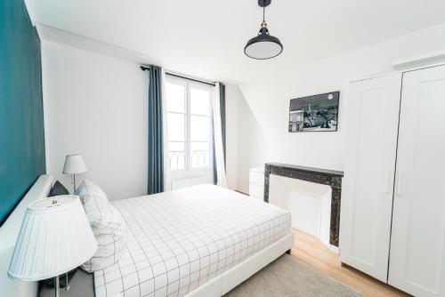 une chambre blanche avec un lit et une cheminée dans l'établissement Charmant 2 pièces à 2 pas du Marais, à Paris