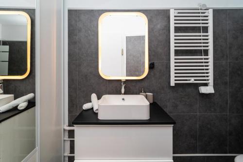 une salle de bain avec un lavabo et un miroir dans l'établissement Charmant 2 pièces à 2 pas du Marais, à Paris