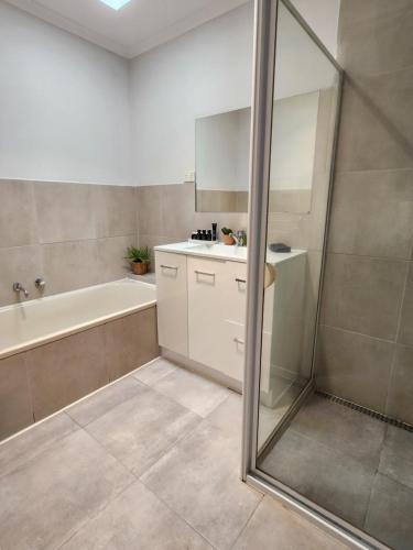 a bathroom with a shower and a tub and a sink at Lbarza Charming & Convenient 3BR Home close to Hospitals & Sporting Grounds in Shepparton