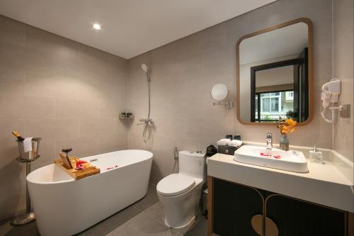 a bathroom with a tub and a toilet and a sink at Le Premier Hotel & Rooftop Bar in Hanoi