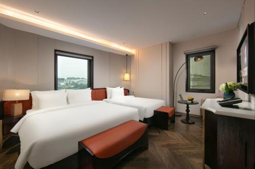 a hotel room with a large bed and a television at Le Premier Hotel & Rooftop Bar in Hanoi