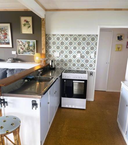 a kitchen with a sink and a microwave at Patons Rock Cutie in Rangihaeata