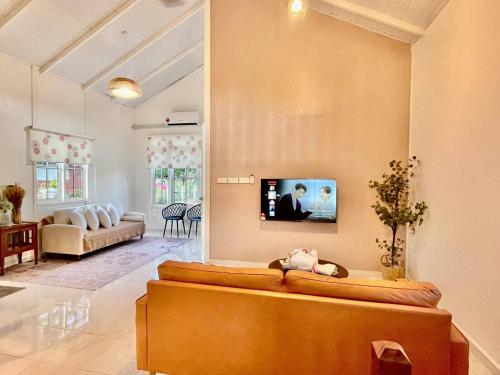 a living room with a couch and a tv on the wall at Rumah Kebun, Jerteh Besut in Kampung Dengir