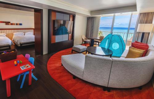 a hotel room with a couch and a bedroom with the ocean at Hyatt Regency Guam in Tumon