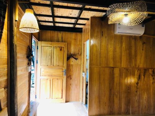 a room with a wooden wall and a door at Nhà của Mỵ in Làng Vat