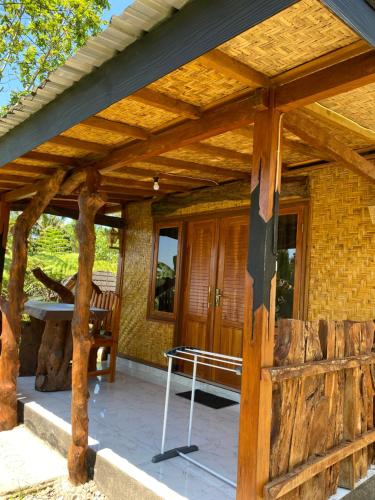 a wooden pergola with a table on a patio at The Alam Bungalow & Restaurant in Tetebatu