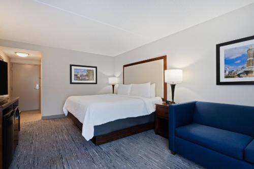 a hotel room with a bed and a blue couch at Holiday Inn Express & Suites Cincinnati Riverfront by IHG in Covington