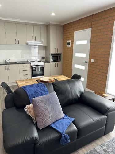 a living room with a black leather couch in a kitchen at Lbarza Brand New Central 1BR Self Contained Apartment in Shepparton