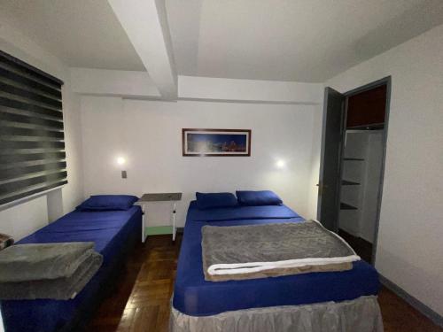 Un dormitorio con dos camas y una mesa y una ventana. en CASA ROMÁN Departamento en Providencia para 3 personas, en Santiago