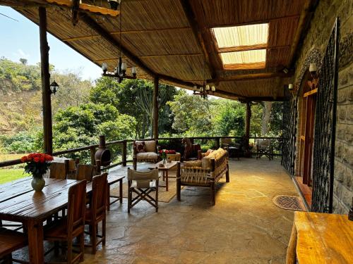 a patio with tables and chairs and a view of the forest at Magical Malewa Retreat in Naivasha