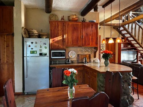 a kitchen with a refrigerator and a table with flowers on it at Magical Malewa Retreat in Naivasha