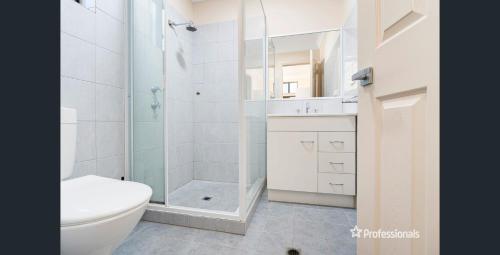 a white bathroom with a shower and a toilet at Pet Friendly Townhouse in Geraldton