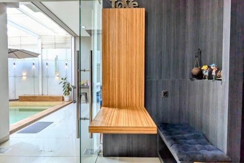 a wooden bench in a room next to a swimming pool at Cottonwood Villa Kuantan Jogja - Pool Netflix Gym in Ngabean