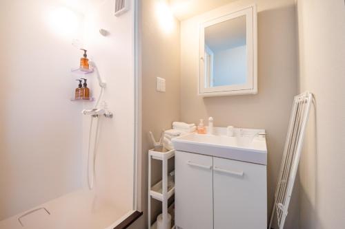 a white bathroom with a sink and a mirror at LOCO Minamiichi in Nara