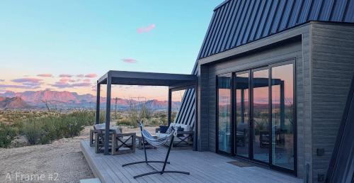 a house with glass doors and a hammock on a deck at Stardust Big Bend Luxury A-Frame#1 with a fab view in Terlingua