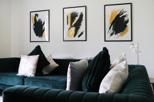 a living room with a green couch and some paintings at Modern 3-Bedroom - VAT Included - Private Drive Parking in Stafford
