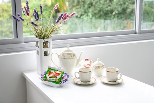a table with three cups and a vase with flowers at Collaroy 3Br Beach Home with Large Pool Ground Floor in Collaroy