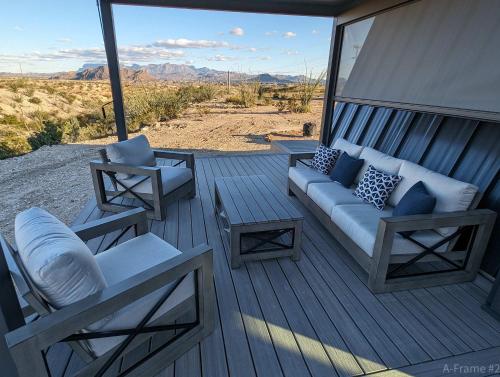 a porch with a couch and a table and chairs at Stardust Big Bend Luxury A-Frame#10 with a fab view in Terlingua