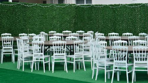 a group of white chairs and a table and a hedge at ATAKUM PALAS OTEL in Samsun