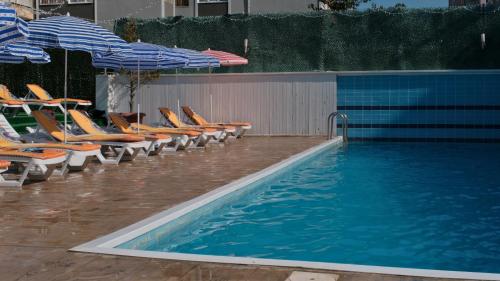 a pool with lounge chairs and umbrellas next to a swimming pool at ATAKUM PALAS OTEL in Samsun