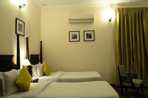 a hotel room with two beds with yellow pillows at Dev Villa in Udaipur
