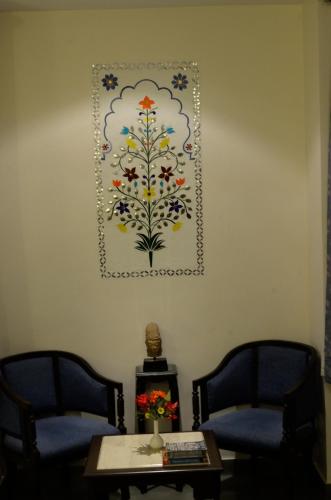 a painting on a wall with two chairs and a table at Dev Villa in Udaipur