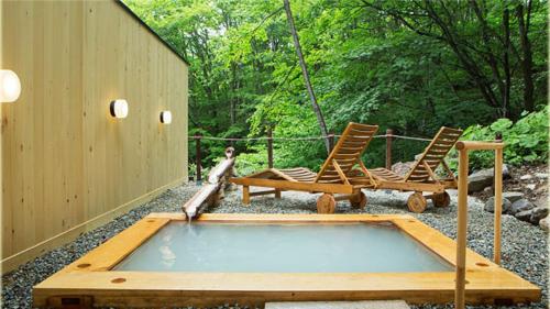 a swimming pool with chairs and a dog standing next to it at Mogamitakayu Zenshichinoyu Ohira in Zao Onsen