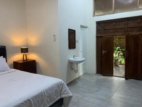 a bedroom with a bed and a sink and a door at Omah Pinter in Beran-kidul