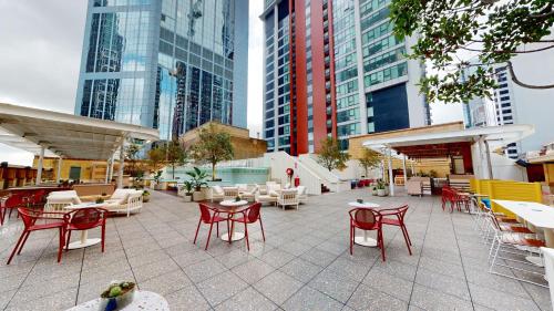a patio with red chairs and tables and buildings at Kimpton Margot Sydney by IHG in Sydney