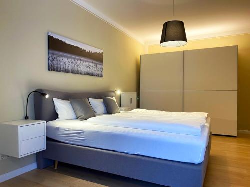 a bedroom with a large white bed and a lamp at MOMENTS Ferienwohnungen - Goschwitzstraße 27 A in Bautzen