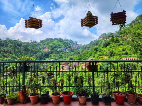 a balcony with potted plants and a view of a mountain at Rashmi Cottage - 4 BHK Villa with Serene Valley Views in Dagshai