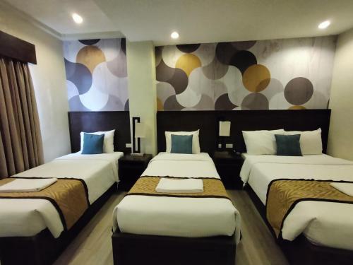 a hotel room with three beds and a mural at Whitewoods Convention and Leisure Hotel by SMS Hospitality in Silang