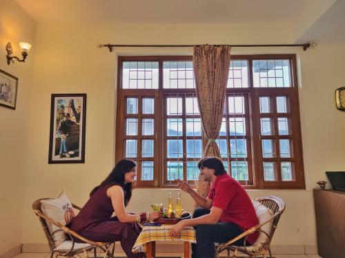 a man and a woman sitting at a table at Rashmi Cottage - 4 BHK Villa with Serene Valley Views in Dagshai