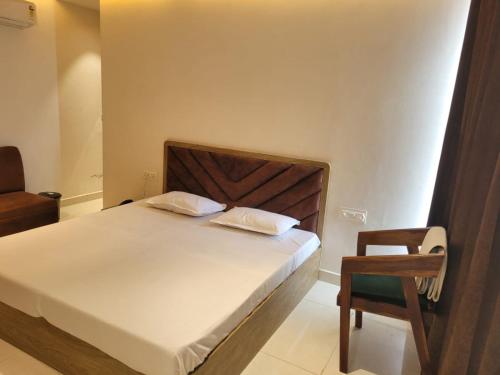 a bedroom with a large bed and a chair at Hotel Royal Vilas in Bharatpur