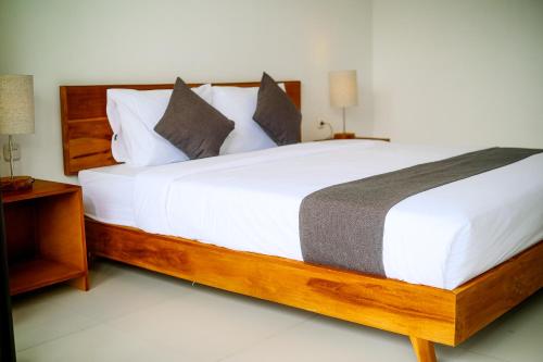 a bedroom with a large bed with white sheets and pillows at Rice Fera Guest House in Canggu