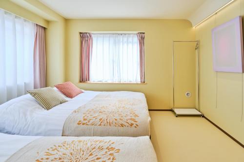 two beds in a small room with a window at 寅ホテル 御徒町 TORA HOTEL Okachimachi in Tokyo
