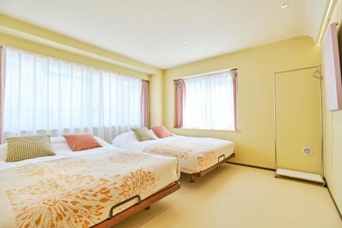 two beds in a room with two windows at 寅ホテル 御徒町 TORA HOTEL Okachimachi in Tokyo