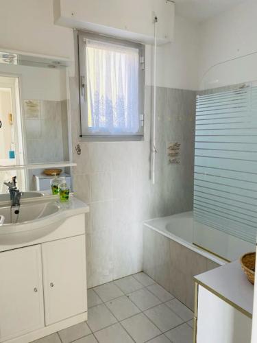 une salle de bain blanche avec un lavabo et une baignoire dans l'établissement Superbe appartement à 50m de la mer, balcon vue mer, 2 chambres, à Cavalaire-sur-Mer