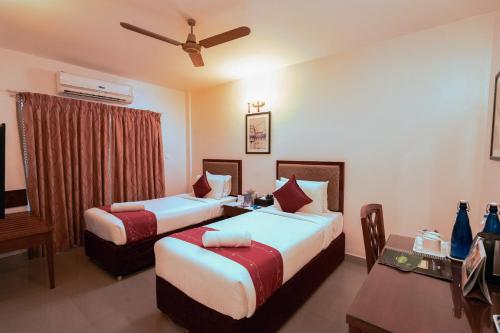 a hotel room with two beds and a table at MGM Vailankanni in Velānganni