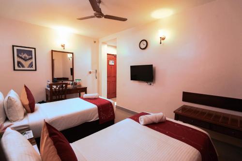 a hotel room with two beds and a television at MGM Vailankanni in Velānganni