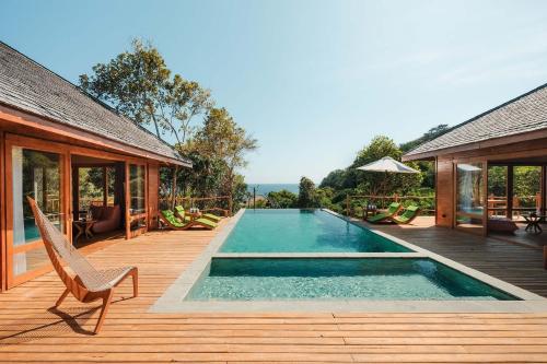 una piscina su una terrazza in legno accanto a una casa di TUNAK Resort Lombok a Bumbang
