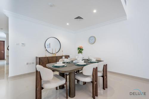 a dining room with a wooden table and white chairs at Deal of the Week 4BR with Pool, Sea & Mountain Views by Deluxe Holiday Homes in Sharm