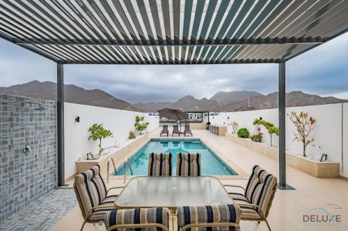 a patio with a table and chairs and a swimming pool at Deal of the Week 4BR with Pool, Sea & Mountain Views by Deluxe Holiday Homes in Sharm