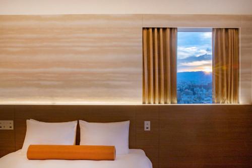 a bedroom with a bed with a large window at karaksa hotel grande Shin-Osaka Tower in Osaka
