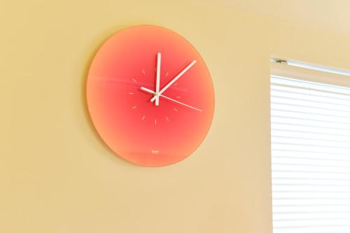 a red clock on a wall next to a window at 寅ホテル 御徒町 TORA HOTEL Okachimachi in Tokyo
