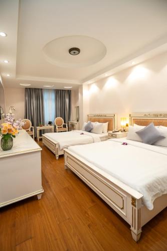 two beds in a large room with wooden floors at Cap Town Hotel in Ho Chi Minh City