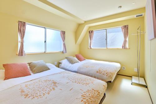 two beds in a room with two windows at 寅ホテル 御徒町 TORA HOTEL Okachimachi in Tokyo