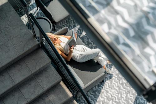 a woman laying on stairs reading a book at Luna Self Check-in Hotel Klaipeda in Klaipėda